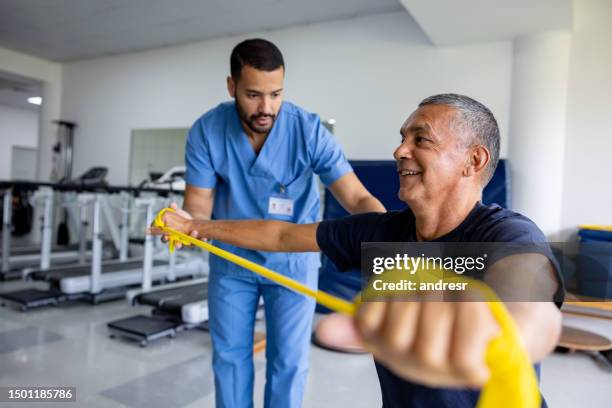 mann, der physiotherapeutische übungen mit einem stretchband macht - occupational therapist stock-fotos und bilder