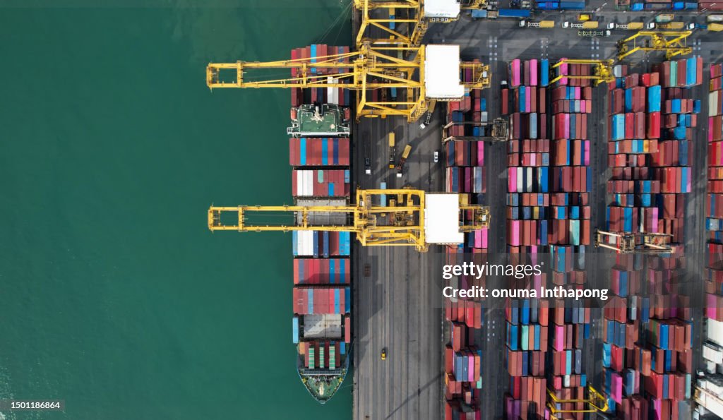 La vista aerea dall'alto sulla nave da carico internazionale per container nel porto industriale di import-export si prepara a caricare container con una grande nave caricatrice di container. attività globale di trasporto e logistica.