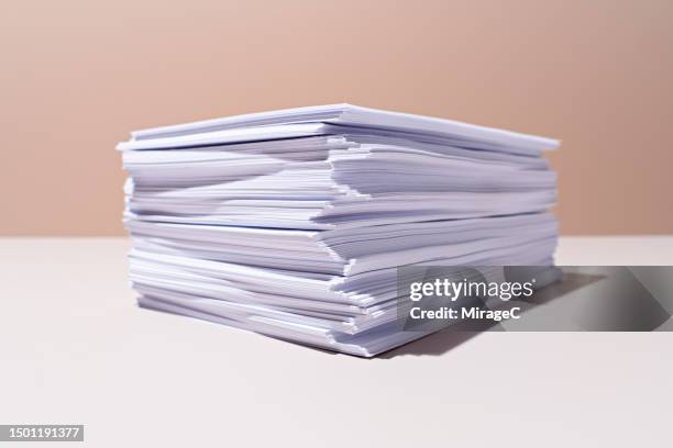 a heap of white paper on beige background - papierstapel stock-fotos und bilder