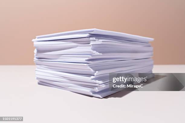 a heap of white paper on beige background - exceso fotografías e imágenes de stock