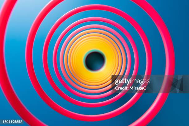 spiral structure inside a pink coiled spring on blue background - metal coil toy stock-fotos und bilder