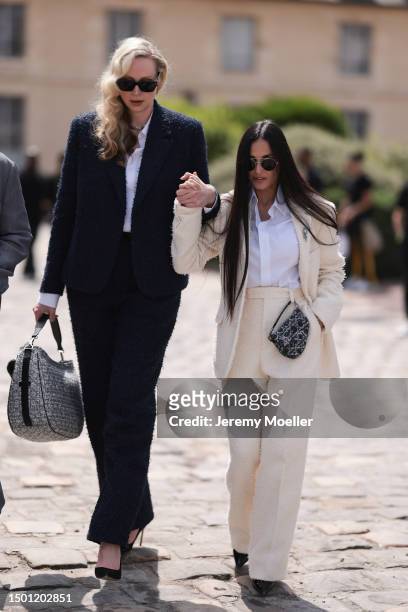 Demi Moore is seen wearing a tweed light creme blazer with shoulder pads and matching creme wide leg tweed pants, white flanell, black heels and...