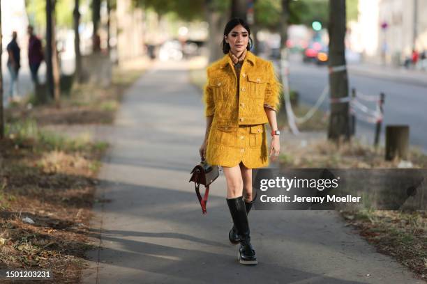 Heart Evangelista wearing a yellow jacket and matching mini yellow skirt, Kenzo beige canvas bag and black boots outside the Kenzo show during the...