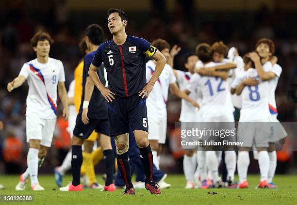 Maya Yoshida of Japan looks dejected as Korea players celebrate defeating Japan during the Men's Football Bronze medal play-off match between Korea...