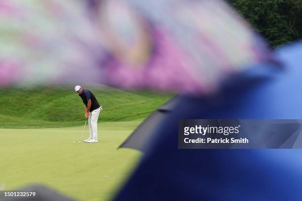 Scottie Scheffler of the United States putts on the fourth green as umbrellas are seen during the third round of the Travelers Championship at TPC...