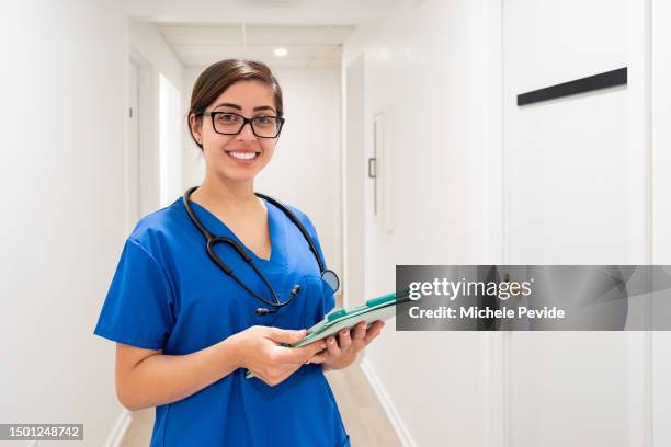 female health care professional at the corredor in a clinic looking at camera - nursing assistant imagens e fotografias de stock