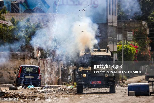 Israeli soldiers fire tear gas canisters from an armoured vehicle during an ongoing military operation in the occupied West Bank city of Jenin on...