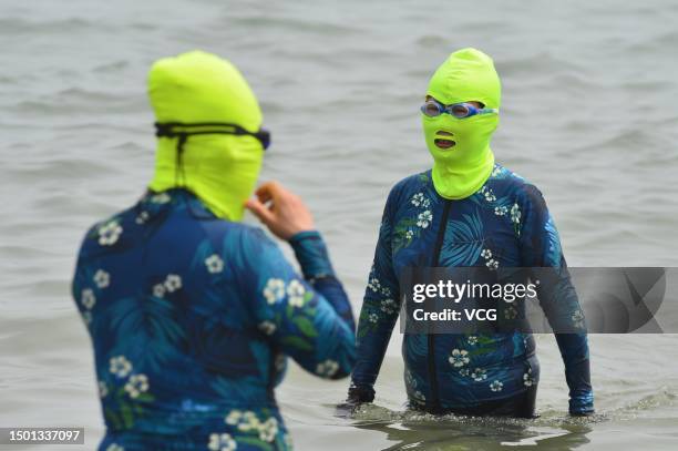 Tourists wearing facekini cool off at a bathing beach amid high temperature on June 24, 2023 in Qingdao, Shandong Province of China.