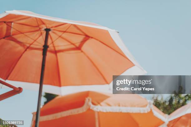 orange parasols against blue sky - ombrellone da spiaggia foto e immagini stock