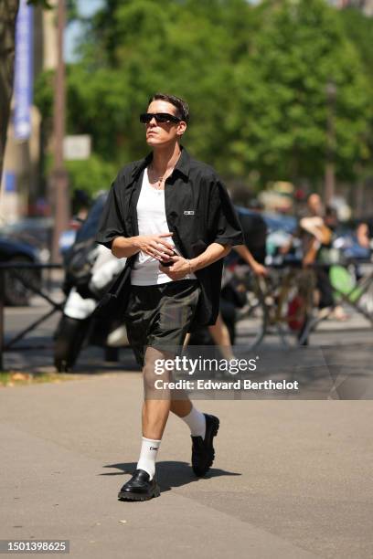 Guest wears black sunglasses, a white tank-top, a black short sleeves shirt from Balenciaga, black suit pants, a silver small chain bracelet from...