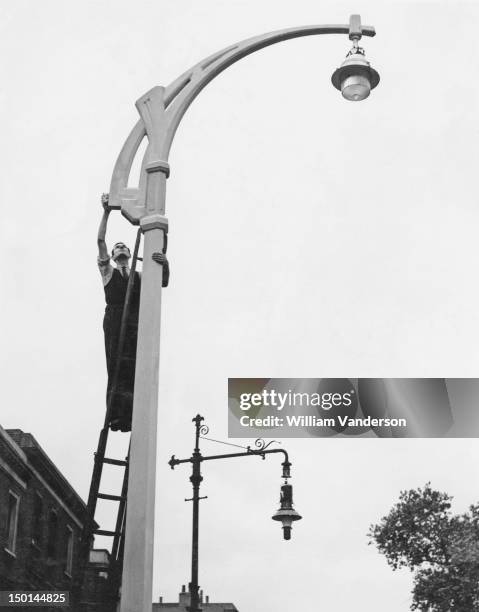 Britain's first concrete street lamp on the Fulham Road in London, 25th September 1936. It contrasts with the old iron type, visible behind.