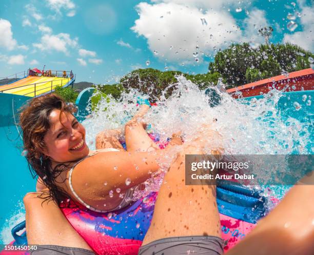 super fun couple in the water park splashing water in the water slide. - water flume stock pictures, royalty-free photos & images