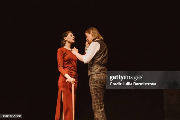beautiful woman in red dress and man in vintage suit standing close while performing on stage in college theater club - comédie musicale photos et images de collection