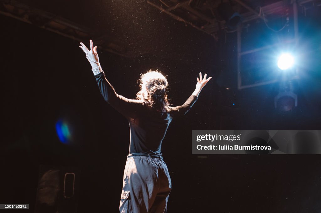 Captivating female performer standing on stage in student theater club during emotional recital