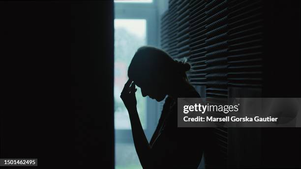 the girl sits in a dark room and suffers a mental breakdown - depression. - com as mãos na cabeça imagens e fotografias de stock
