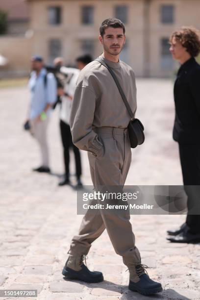 Álvaro Mel is seen wearing a beige big sweater, crossbody Dior leather bag, matching beige suit pants and black and beige boots outside Dior Homme...