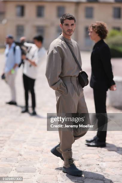 Álvaro Mel is seen wearing a beige big sweater, crossbody Dior leather bag, matching beige suit pants and black and beige boots outside Dior Homme...