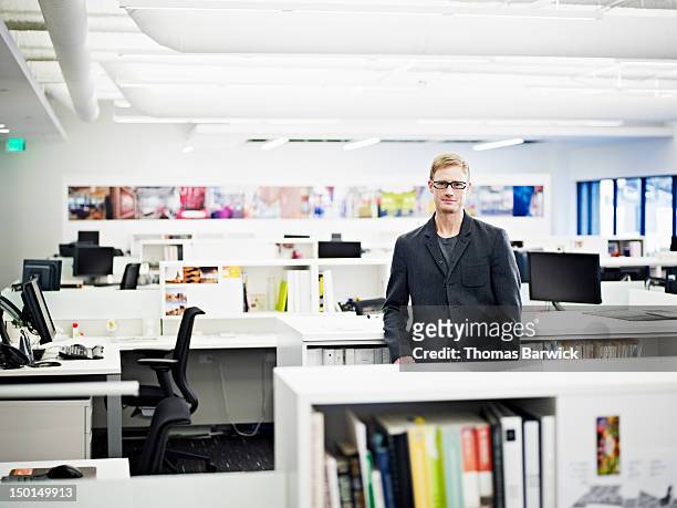 businessman standing in empty office smiling - un seul homme d'âge moyen photos et images de collection