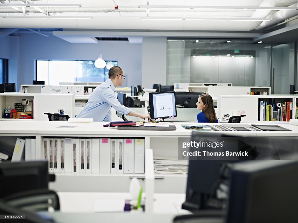 Coworkers discussing project at computer in office