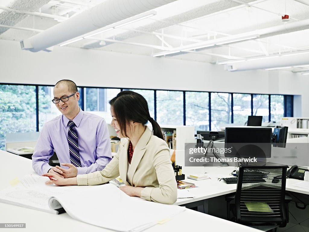 Two architects examining plans in office