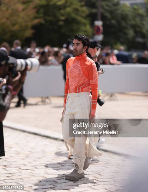 Abdulla Al Abdulla is seen wearing a orange logo neon turtleneck, beige suit pants with skirt and beige brown boots outside Dior Homme during the...
