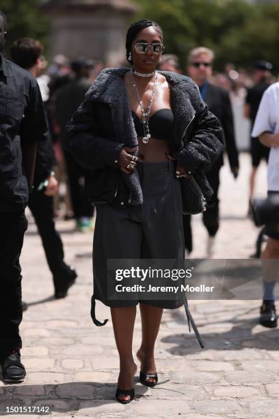 Tiwa Savage is seen wearing a shiny shades, black bra, black and fur jacket, grey capri pants and black heels outside Dior Homme during the Menswear...