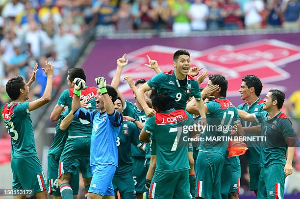 Mexico's forward Oribe Peralta is carried by Mexico's midfielder Javier Cortes as the players celebrate winning the men's football final match...