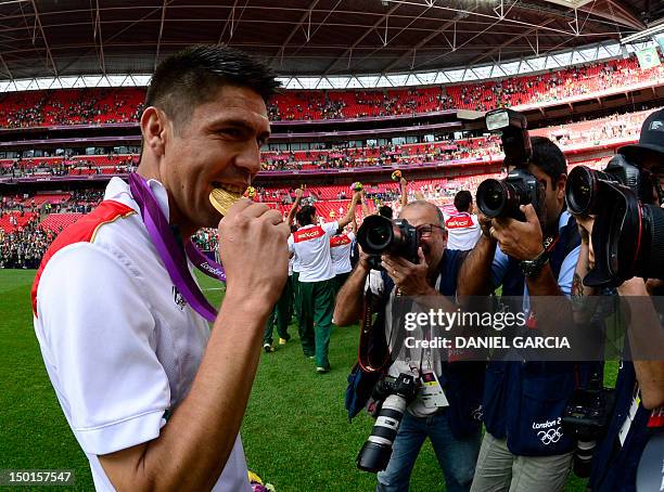 LENSMexico's forward Oribe Peralta bites his gold medal after the podium ceremony of the men's football final at Wembley stadium during the London...