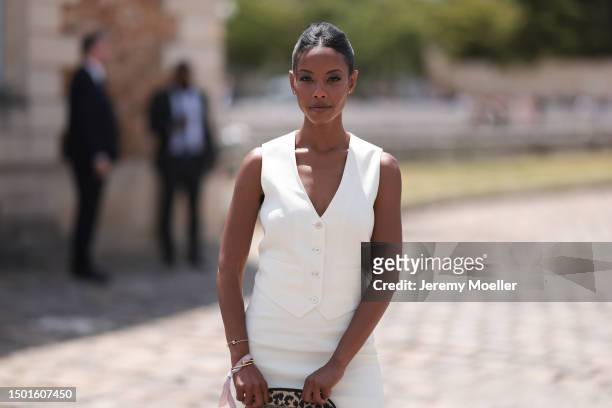 Fashion Week guest is seen wearing a creme white vest top and matching creme white mini skirt, Dior leo animal print beauty clutch and matching leo...