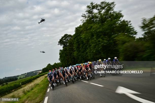 Tour de France organisation and television broadcast helicopters hover overhead as the pack of riders cycles during the 4th stage of the 110th...