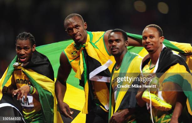 Yohan Blake, Usain Bolt, Nesta Carter and Michael Frater of Jamaica celebrate next to the clock after winning gold and setting a new world record of...