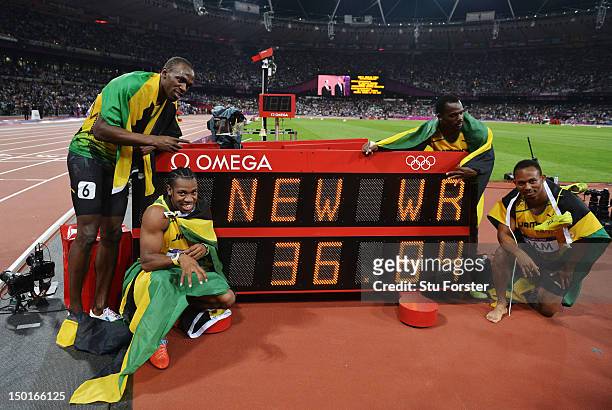 Usain Bolt, Yohan Blake, Michael Frater and Nesta Carter of Jamaica celebrate next to the clock after winning gold and setting a new world record of...