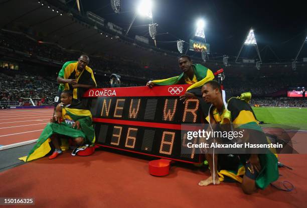 Usain Bolt, Yohan Blake, Michael Frater and Nesta Carter of Jamaica celebrate next to the clock after winning gold and setting a new world record of...