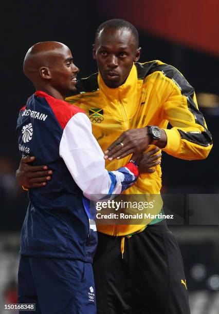 Gold medalist Mohamed Farah of Great Britain hugs Usain Bolt of Jamaica as he stands on the podium during the medal ceremony for the Men's 5000m...