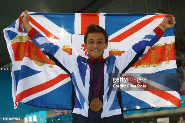 Bronze medallist Tom Daley of Great Britain poses with the national flag after the medal ceremony for the Men's 10m Platform Diving Semifinal on Day...