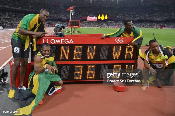 Usain Bolt, Yohan Blake, Michael Frater and Nesta Carter of Jamaica celebrate next to the clock after winning gold and setting a new world record of...