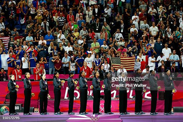 Players from the United States stand on the podium during the playing of the United States national anthem after they received their gold medlas...