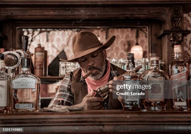 handsome black cowboy in an authentic wild west setting - handsome cowboy stock pictures, royalty-free photos & images