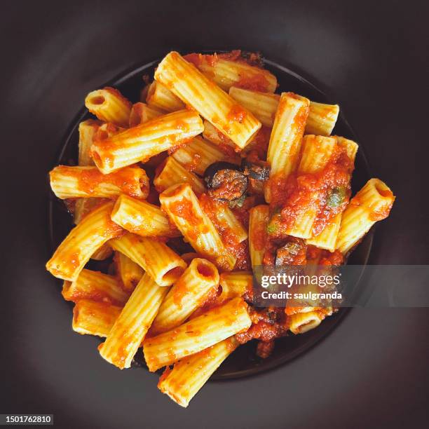 rigatoni alla puttanesca on a black plate - tomato sauce stock pictures, royalty-free photos & images