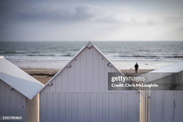 beach huts at juno beach, saint aubin sur mer in normandy with person in the distance. - juno beach normandy stock-fotos und bilder