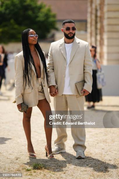 Guest wears pink sunglasses, a beige blazer jacket, a beige matching linen short skirt, beige matte leather strappy heels sandals, a beige with navy...