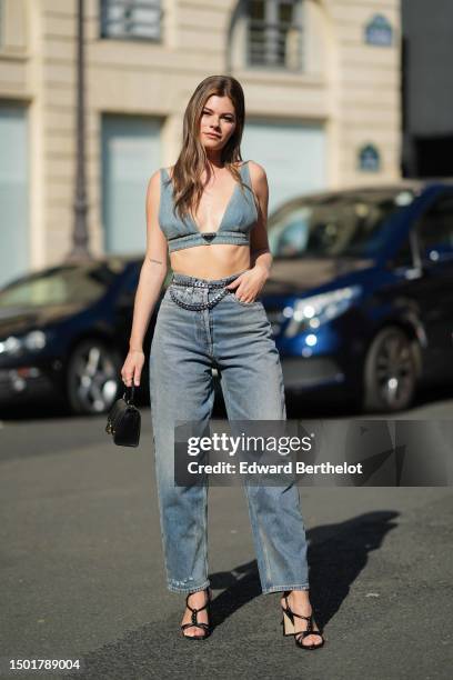 Alexandra Tango wears a blue faded denim V-neck / cropped tank-top from Prada, blue denim large pants, a silver large chain belt, a small gold chain...