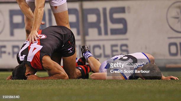 Nathan Lovett-Murray of the Bombers and Lachlan Hansen of the Kangaroos lie on the ground injured during the round 20 AFL match between the Essendon...