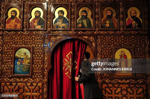 Man looks behind a curtain in front of the altar room at the Coptic Markus church in Frankfurt/M., western Germany during Christmas celebrations...