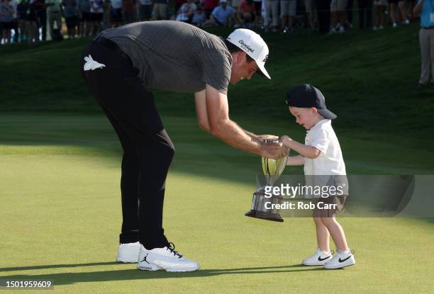 Keegan Bradley of the United States is awarded a trophy by son Cooper Bradley after winning the final round of the Travelers Championship at TPC...