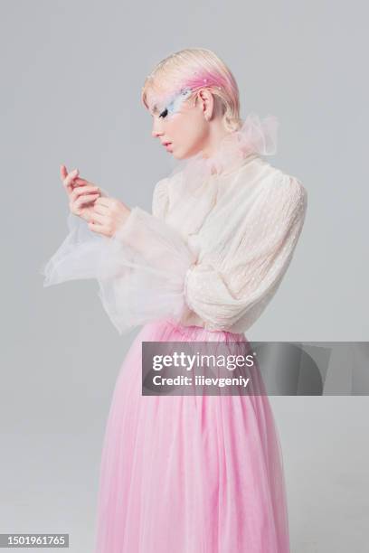 blonde girl in white blouse in studio on white background. short pink hair. model in skirt. beauty makeup with feather. style and fashion. haute couture - haarkleur stockfoto's en -beelden