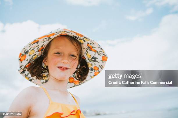 retro-style portrait of a cute little girl wearing a sun hat - ankle deep in water stock pictures, royalty-free photos & images