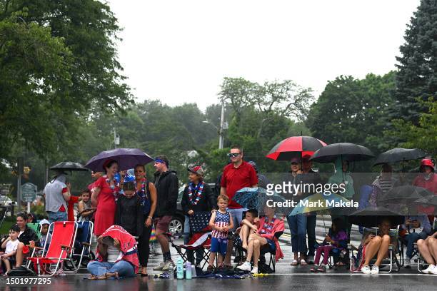People huddle under umbrellas during a rainstorm before a Fourth of July parade in Cape Cod on July 4, 2023 in Orleans, Massachusetts. Today marks...