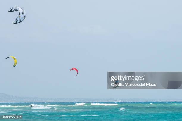Man is seen flying while kite surfing during a summer day at the crystal clear turquoise waters of Corralejo Beach, known as "Grandes Playas de...