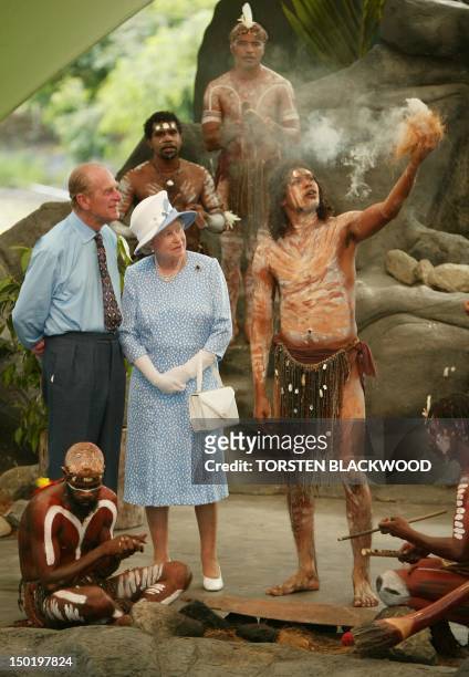Britain's Queen Elizabeth II and her husband Britain's Prince Philip, Duke of Edinburgh watch Tjapukai Aborigines light a ceremonial fire during a...